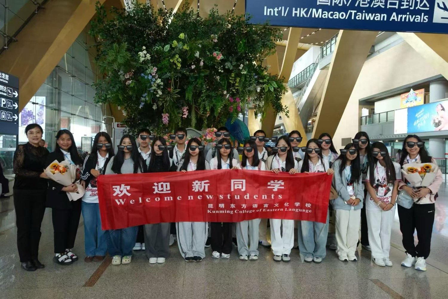 A student group greeted by KCEL staff with flowers at the Kunming Changshui International Airport arrivals hall